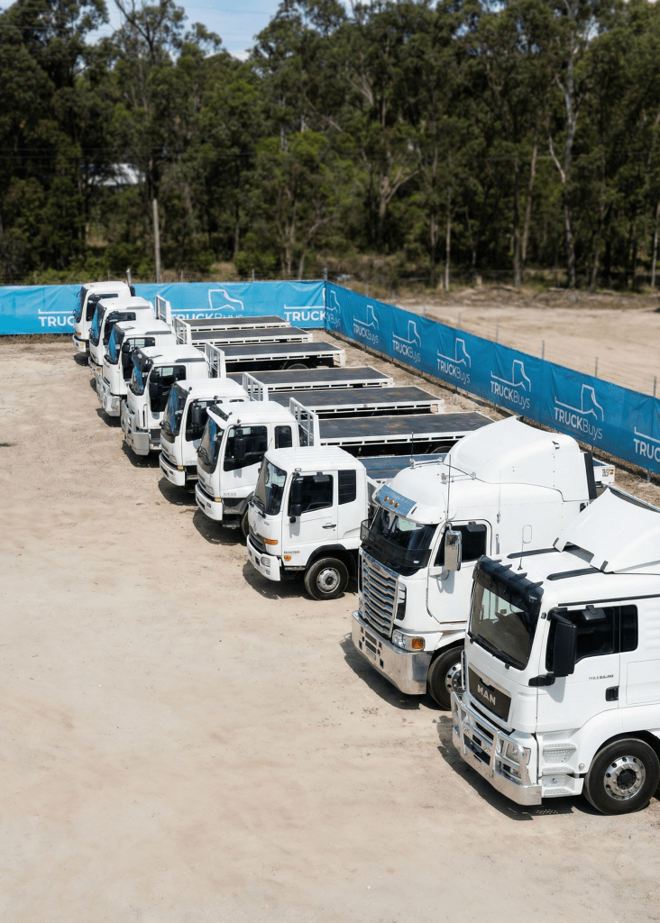 Side view of multiple white commercial trucks parked in a lot